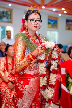 Bride in traditional attire during a vibrant wedding ceremony holding a floral garland.