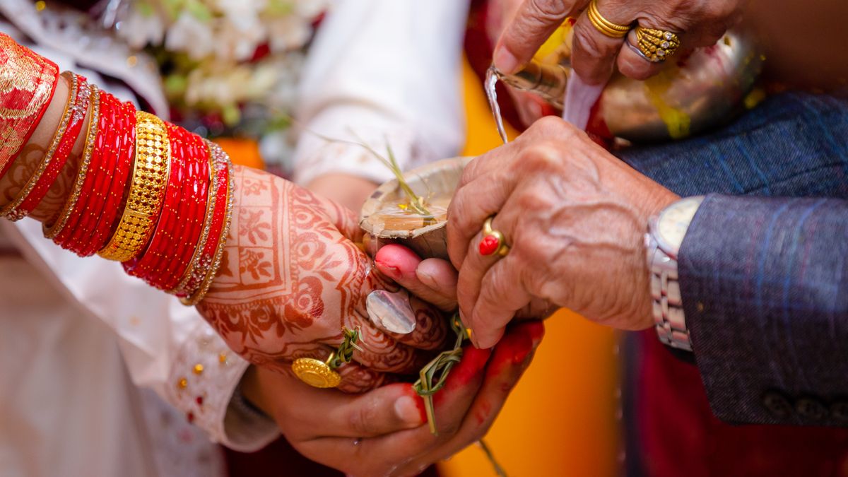 Henna-decorated hands with red bangles at a traditional ritual (Valaikappu Catering in Vellore)