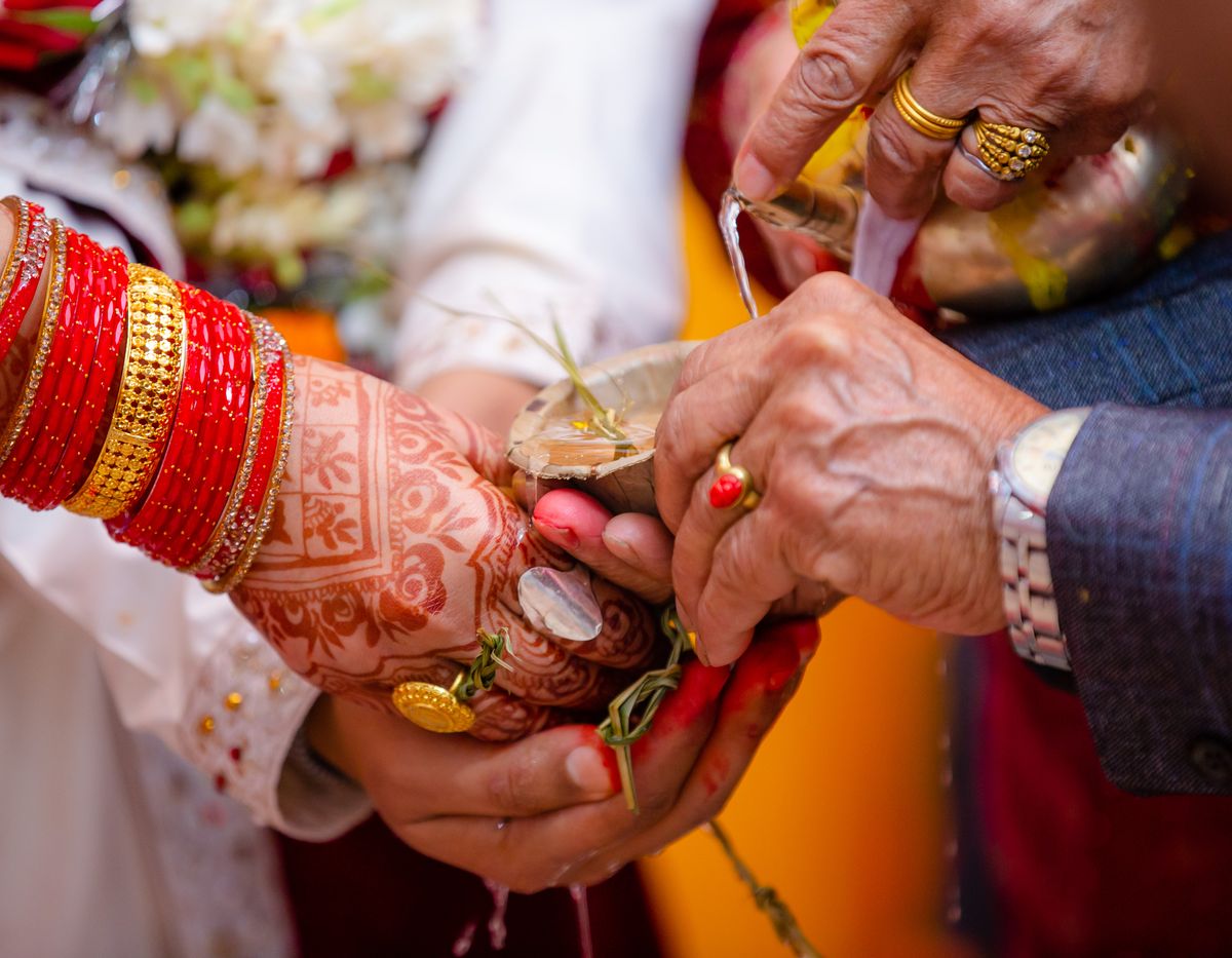 Henna-decorated hands with red bangles at a traditional ritual