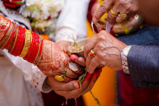 Colorful close-up of traditional Indian wedding ritual with henna and red bangles.