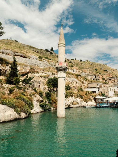 Free A historic mosque minaret rising from turquoise waters in Halfeti, Türkiye, under a bright blue sky. Stock Photo