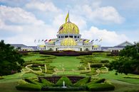 View of the Istana Negara Palace in Kuala Lumpur with lush gardens and clear blue sky.