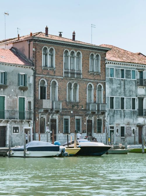 Free Scenic view of historic Venetian buildings along a tranquil canal under clear blue skies. Stock Photo
