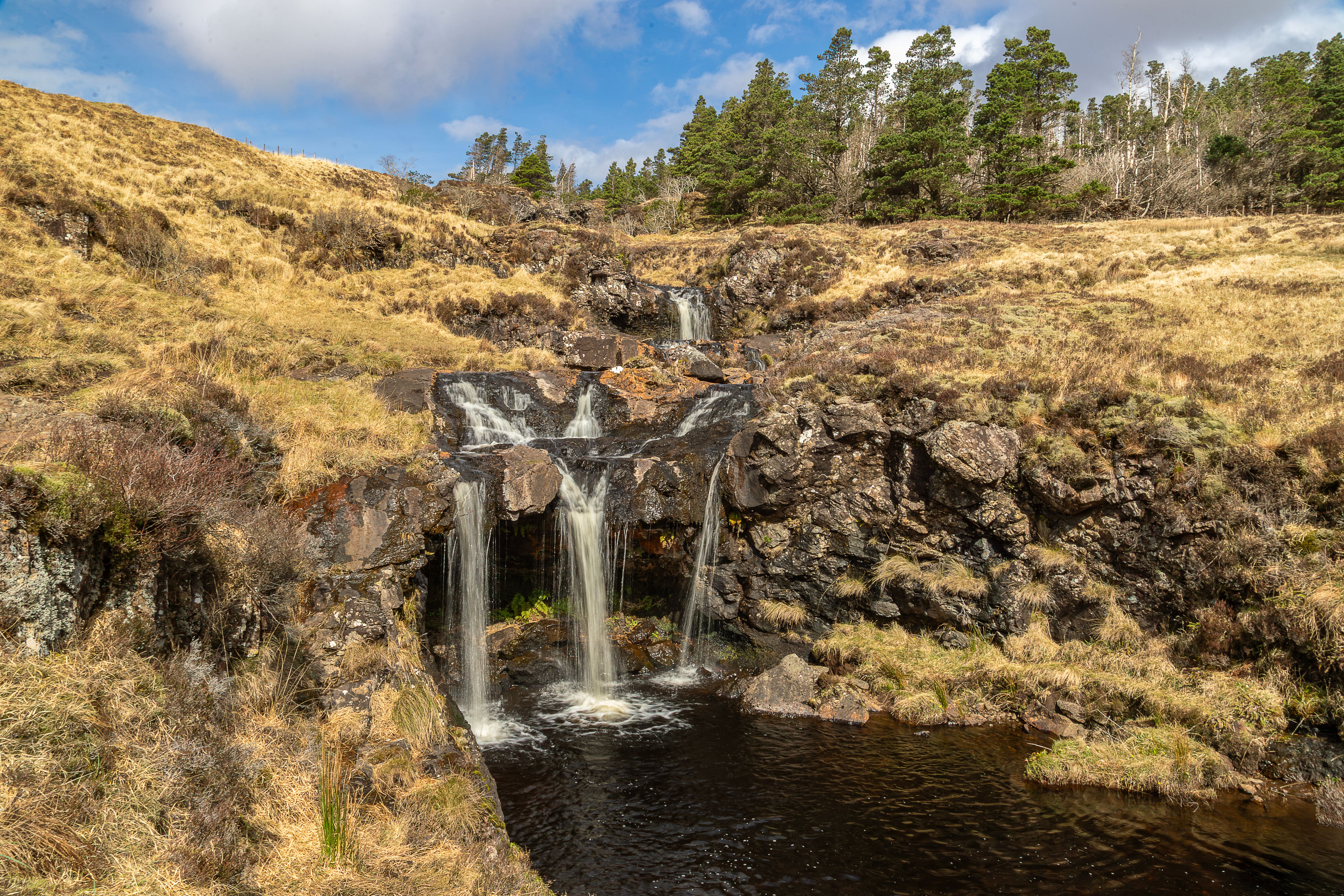 Beautiful waterfall in the Scottish Highlands with natural rock and lush landscape.