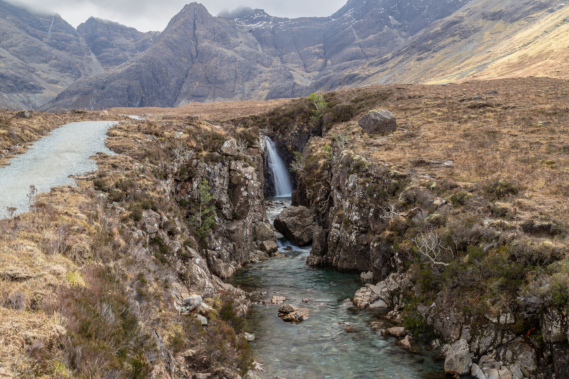 A chain of clear blue-green pools and small waterfalls in Glen Brittle below the jagged Black Cuillin ridge on the Isle of Skye