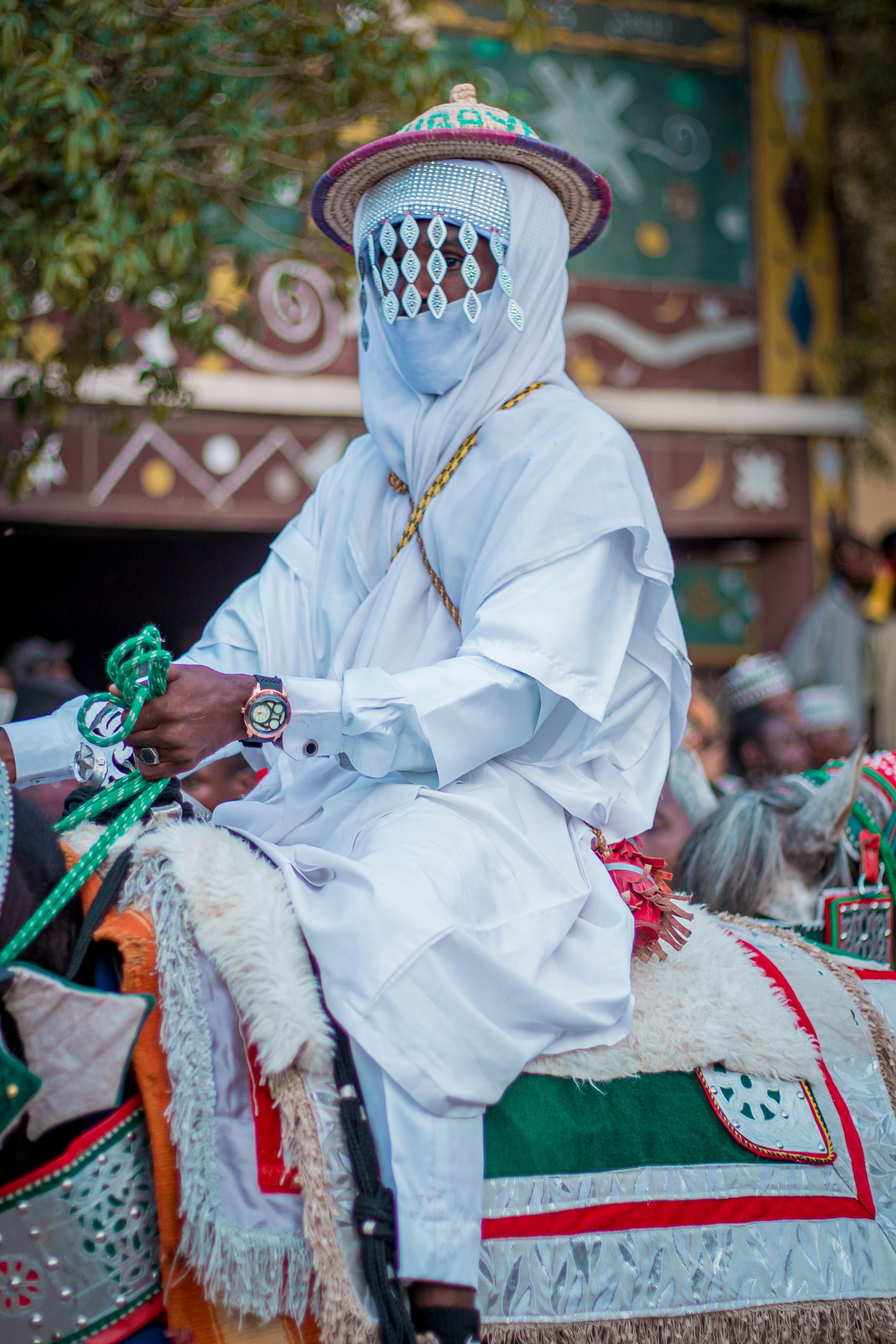 A rider in traditional Nigerian attire participates in a cultural parade, displaying rich cultural heritage and vivid colors.