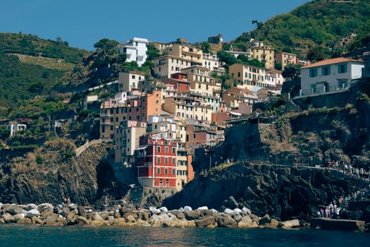 Colorful hillside view of the coastal village in Liguria, Italy, with vibrant buildings and rugged cliffs.