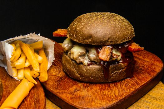 Close-up of a delicious gourmet burger with bacon and cheese, paired with crispy french fries.