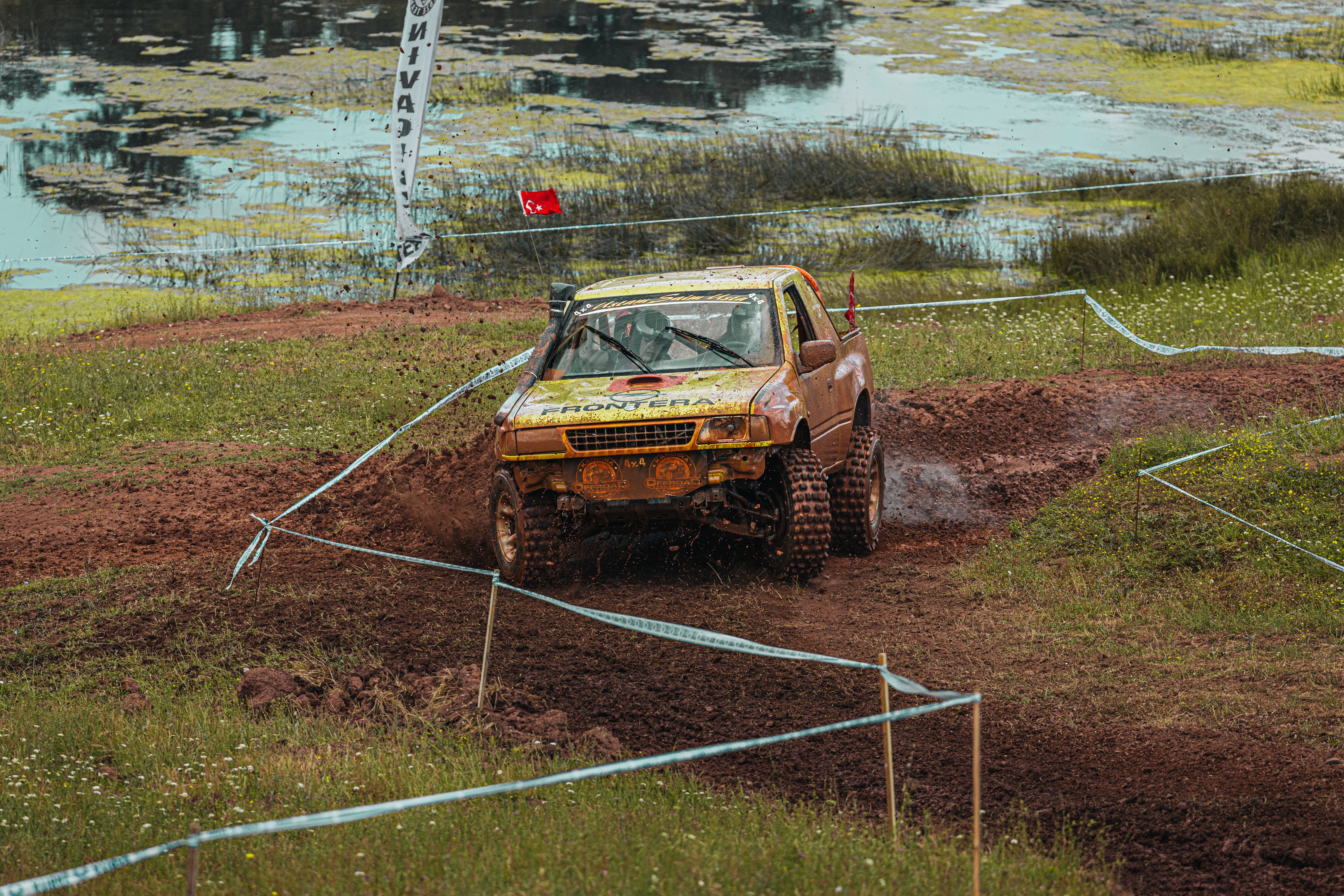 Off-road rally car skillfully navigates a muddy track, showcasing thrilling motorsport action.