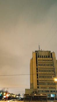 暮光下，一座高大的办公楼闪闪发光，展现了城市建筑与生活的风貌