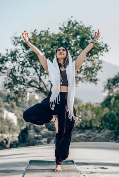 Woman practicing yoga tree pose outdoors in serene nature scene.