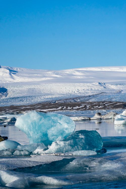 Free A breathtaking view of icebergs floating in an Icelandic glacial lagoon, under a clear blue sky. Stock Photo
