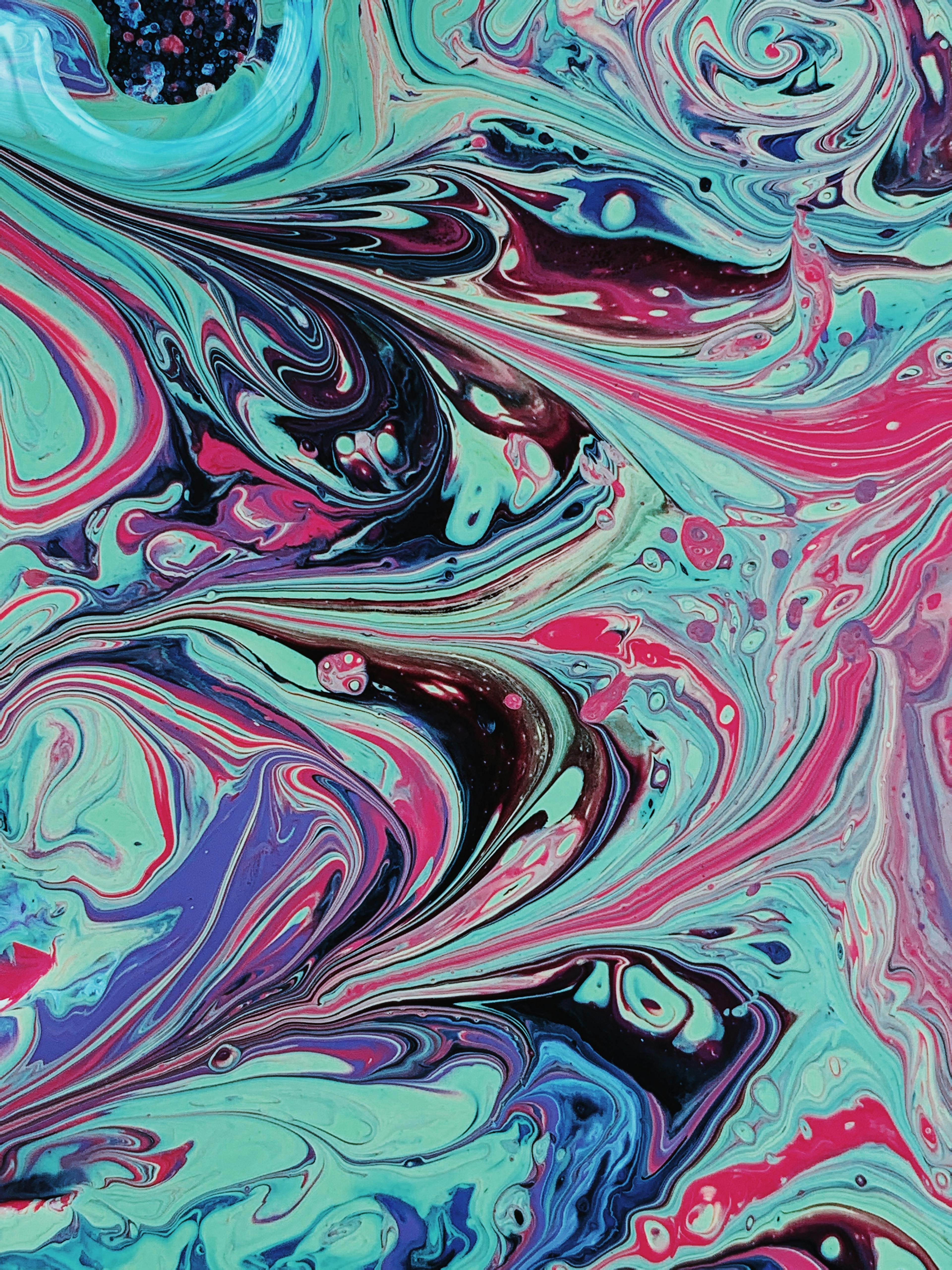 Top view of bright colors of green black pink purple mixed into composition