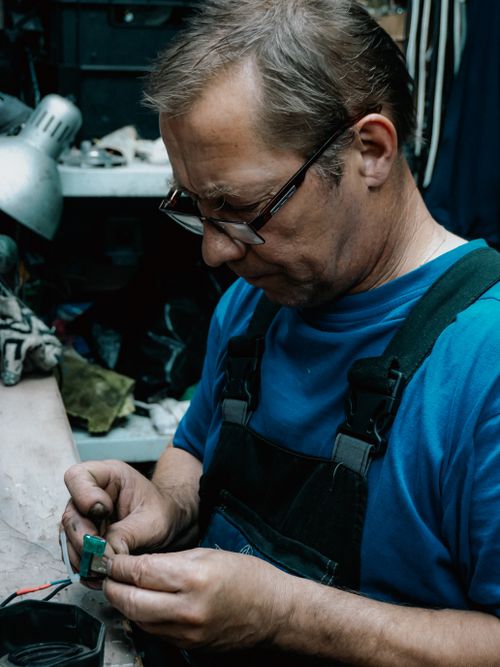 Free Experienced craftsman focuses on intricate detail in a cluttered workshop environment. Stock Photo