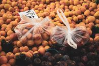 Plastic bags of apricots and plums at a vibrant Turkish market stall. Fresh produce in Alanya, Türkiye.