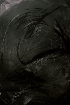 这块带有富有表现力粉笔污迹的黑色黑板引人入胜，非常适合用作背景或纹理