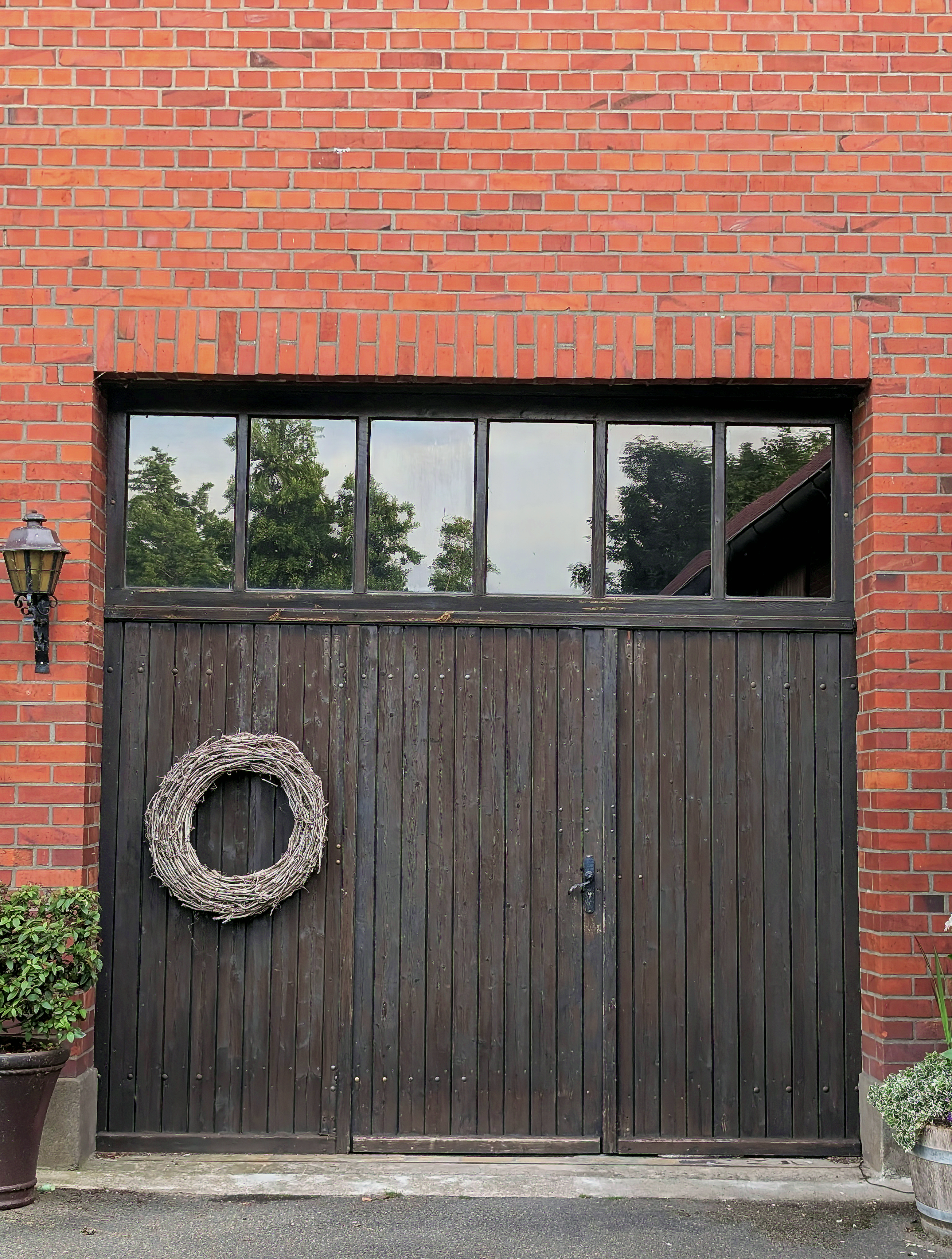 A rustic garage with wooden doors, brick walls, and a decorative wreath, perfect for home decor themes.