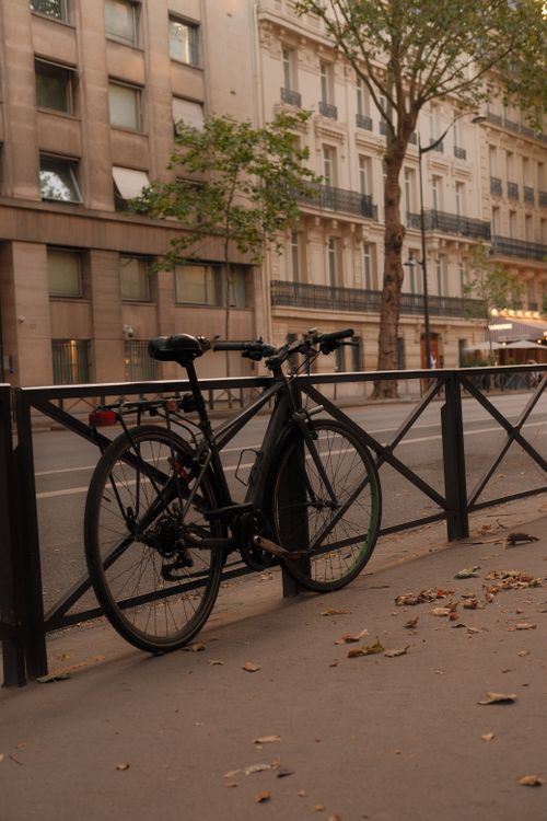 Free Bicycle parked on a Parisian street with classic French architecture in the background. Stock Photo