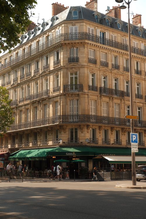 Free Elegant Parisian building on a sunny day in France, with a bustling cafe below. Stock Photo