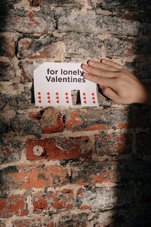 Free Person Holding a Paper Taped on a Wall Stock Photo