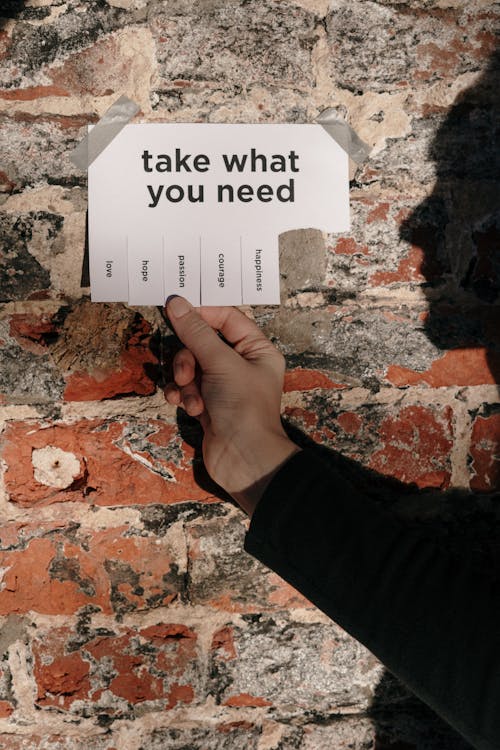 Free Person Holding a Paper Taped on a Wall Stock Photo