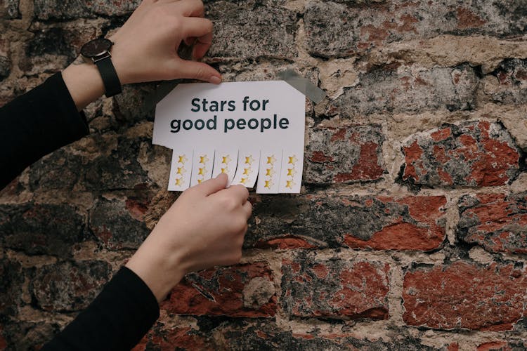 Person Holding A Paper Taped On A Wall