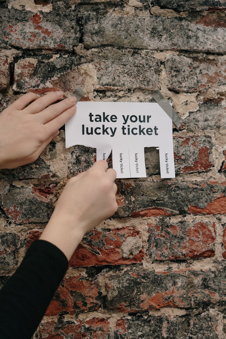 Person Holding A Paper Taped On A Wall