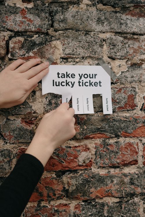 Free Close-up of hands pulling a lucky ticket from paper on a rustic brick wall. Stock Photo
