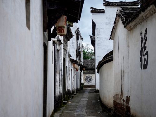 Free Serene view of a narrow alley in a traditional Chinese village with whitewashed walls and decorative elements. Stock Photo
