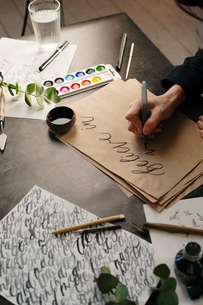 Hand practising brush calligraphy at a studio desk — photo by cottonbro studio on Pexels