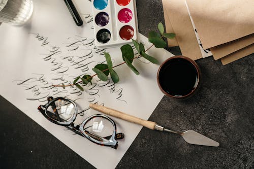Eyeglasses Beside Eucalyptus Leaves on White Paper with Calligraphy Text