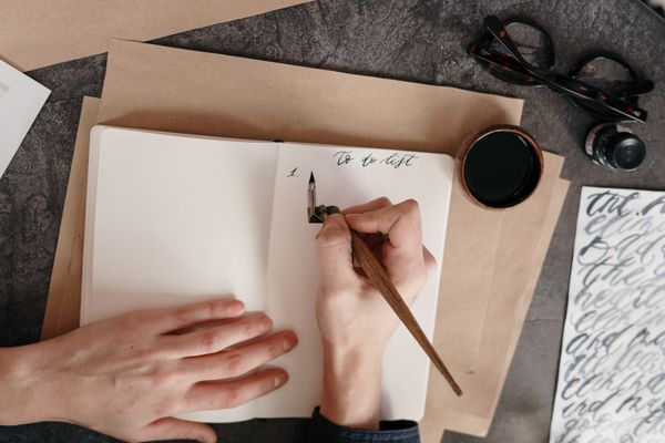 Handwritten list beside a dip pen and ink — photo by cottonbro studio on Pexels