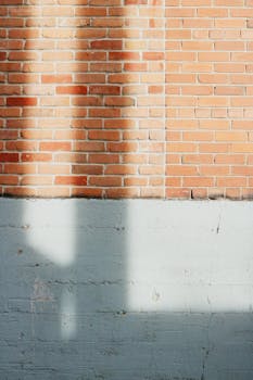 Vertical shot of brick and cement wall with dramatic shadows during golden hour lighting.