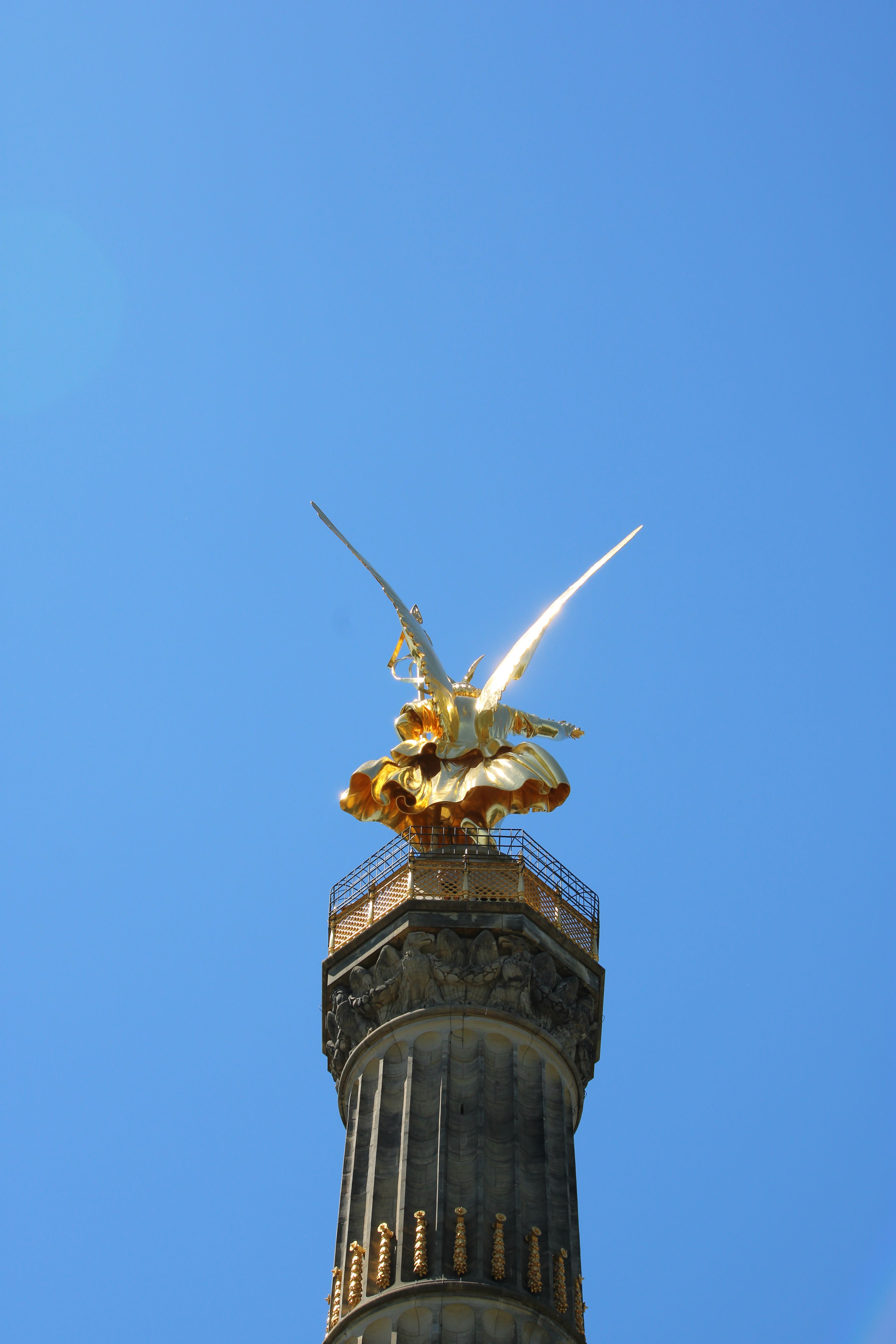 Berlin's Victory Column with golden statue against a vibrant blue sky.