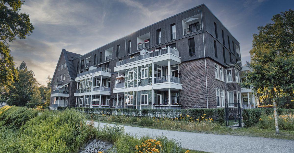 Modern apartment building surrounded by greenery during day.