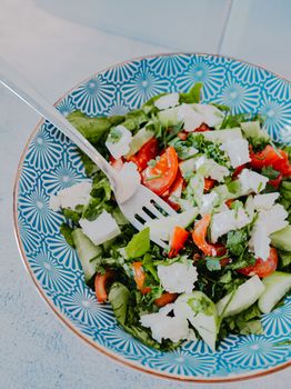 Vibrant Greek salad with fresh vegetables and feta cheese in a patterned bowl.