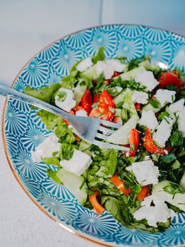 Vibrant Greek salad with feta, cucumbers, and tomatoes in a ceramic bowl, featuring fresh ingredients.