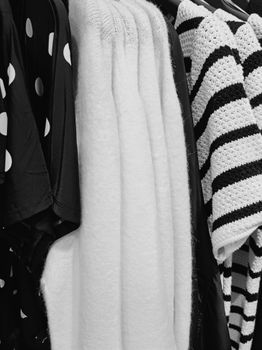Black and white clothing arranged on a rack showcasing stripes and polka dots.