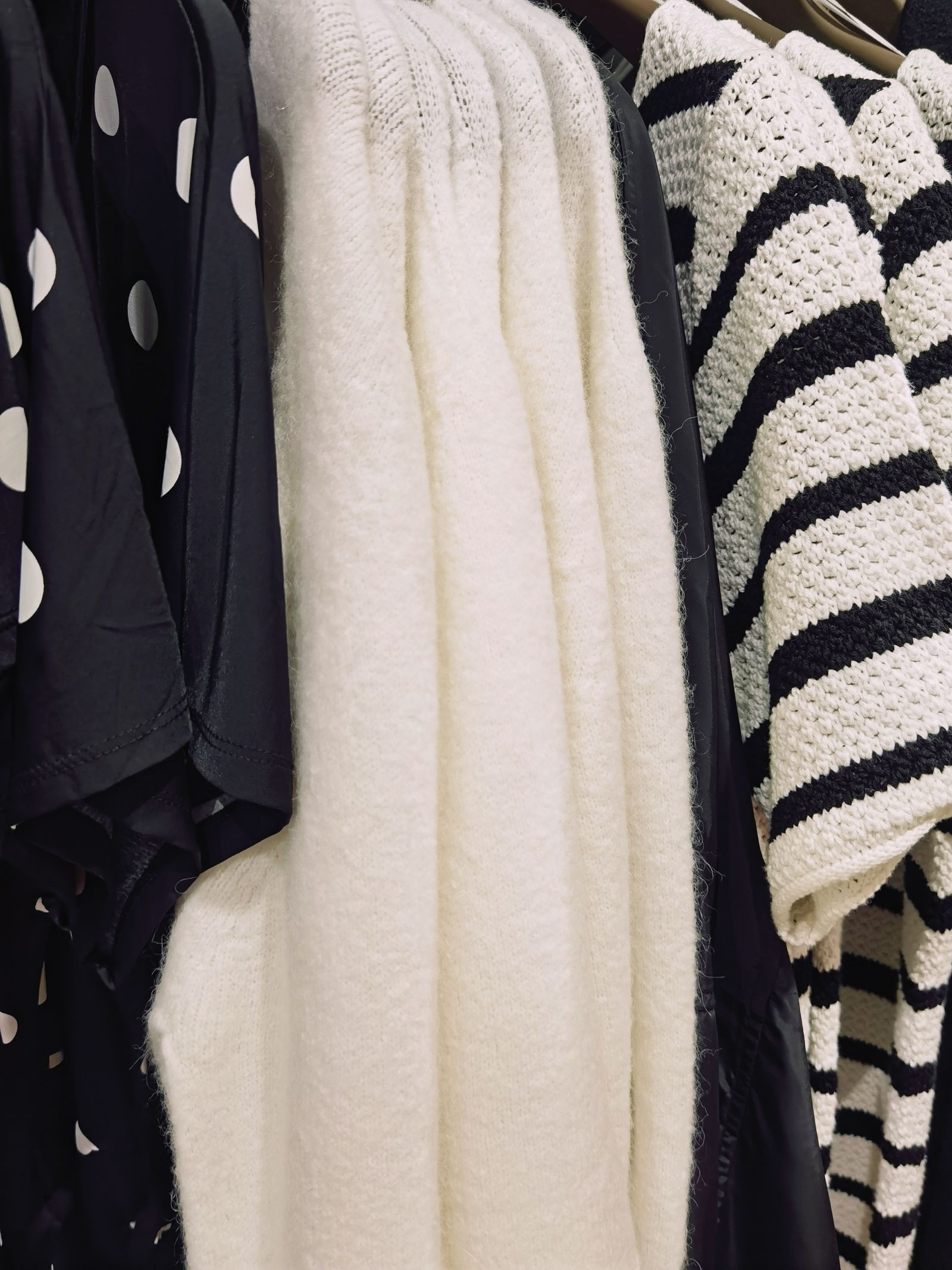 Black-and-white patterned shirts and knits hanging on a rail