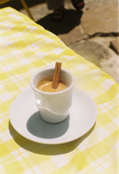 Free A cup of traditional Portuguese drink garnished with a cinnamon stick, set on a sunny table in Lisbon. Stock Photo