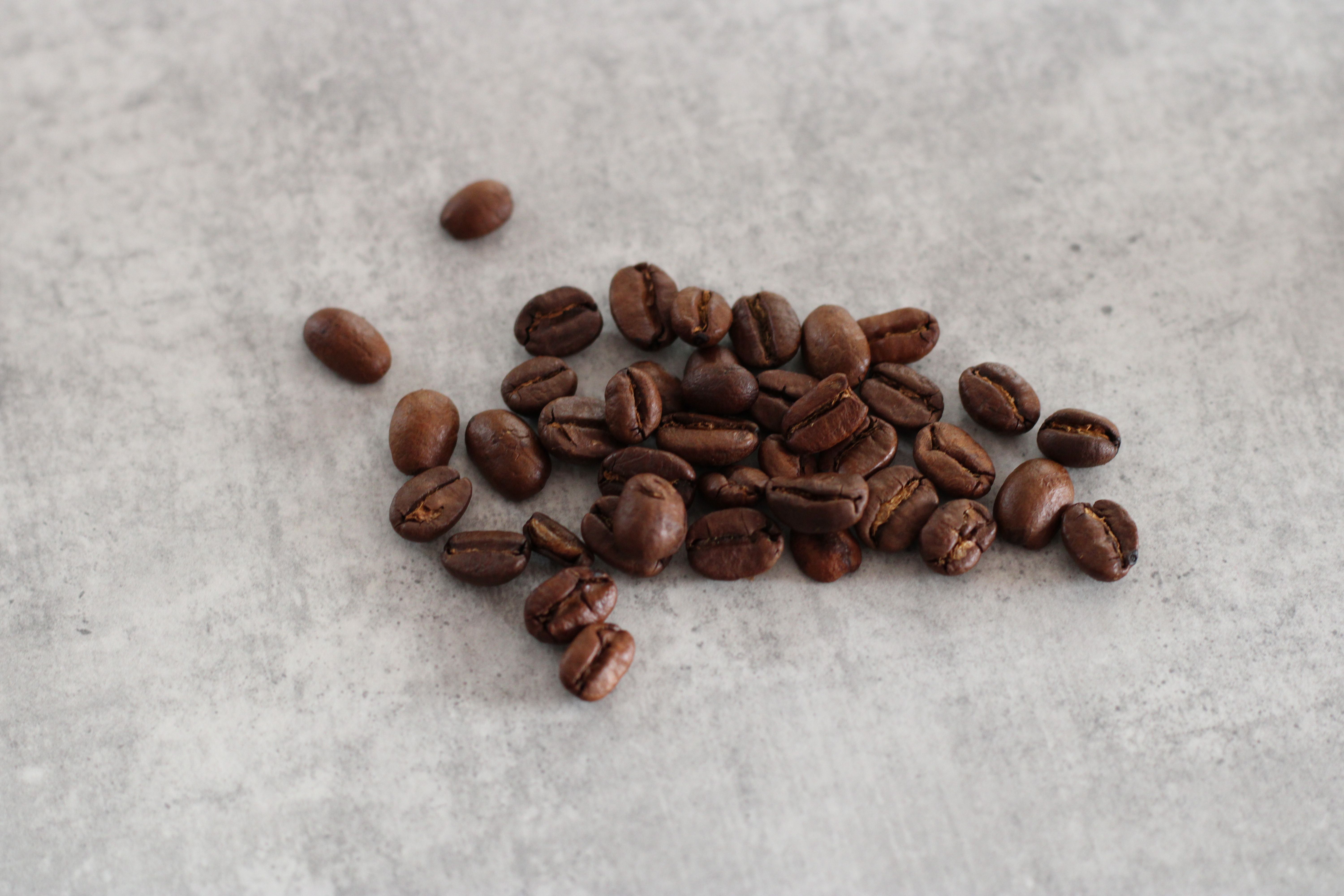 Close-up of roasted coffee beans on a gray textured background, perfect for cafe themes.