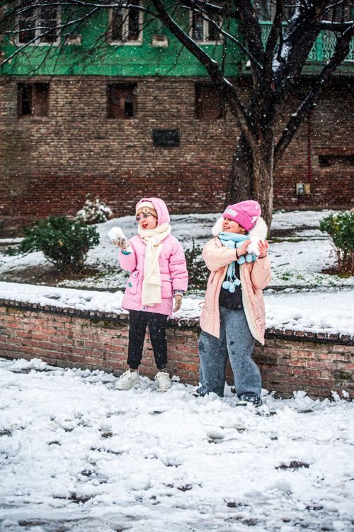Free Two children in winter clothing enjoying a snowy day in the park. Stock Photo
