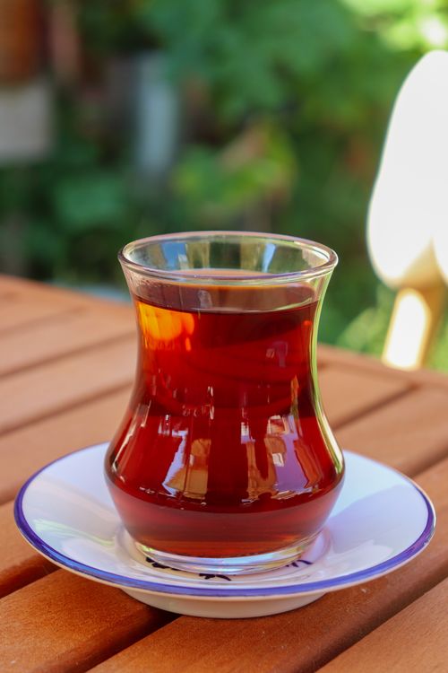 Free A glass of Turkish tea served in a traditional tulip-shaped glass, outdoors on a wooden table. Stock Photo