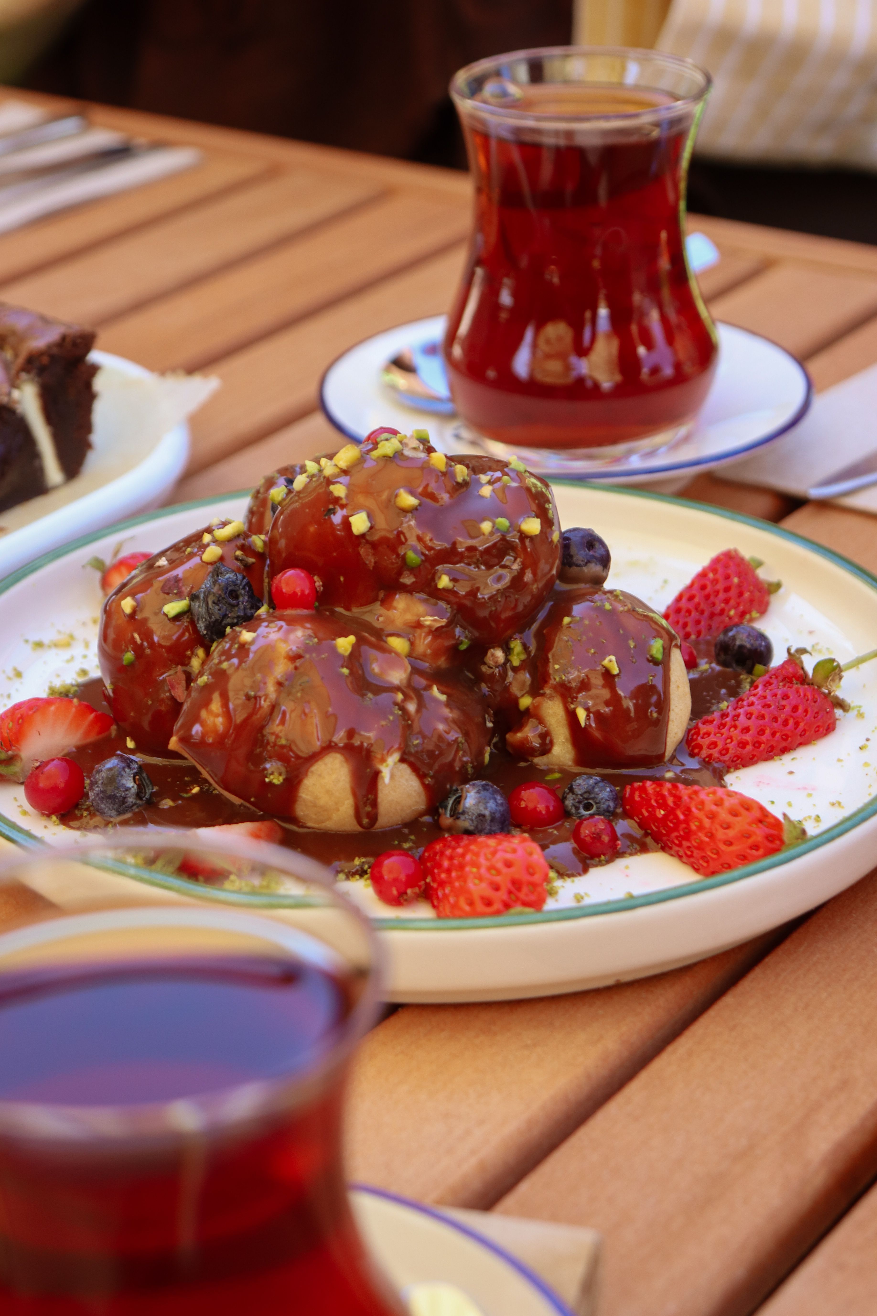 Turkish tea served with delectable pastries and fresh berries on an outdoor table.