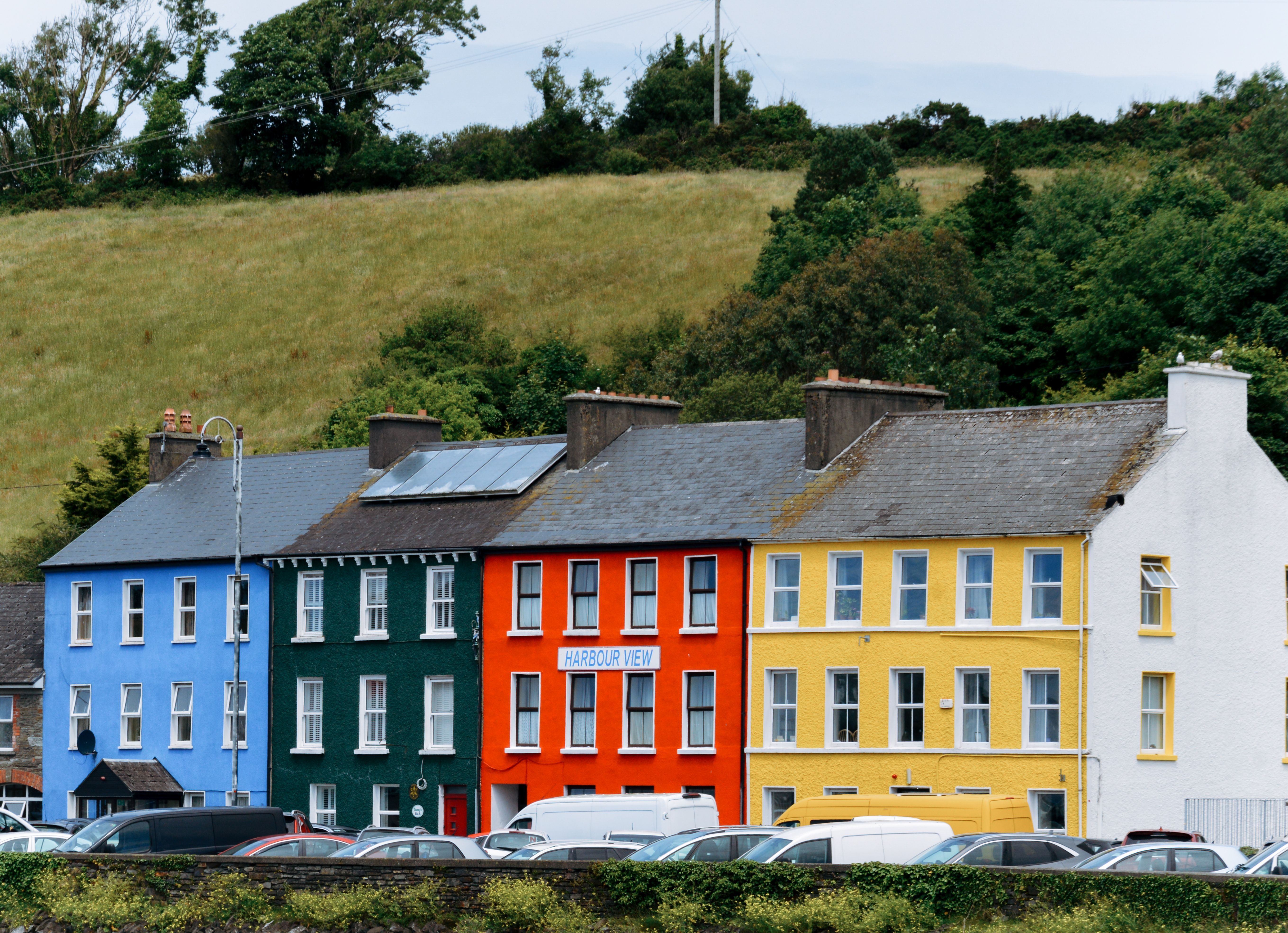 Vibrant row houses in Bantry, Ireland, surrounded by lush greenery and charming architecture.