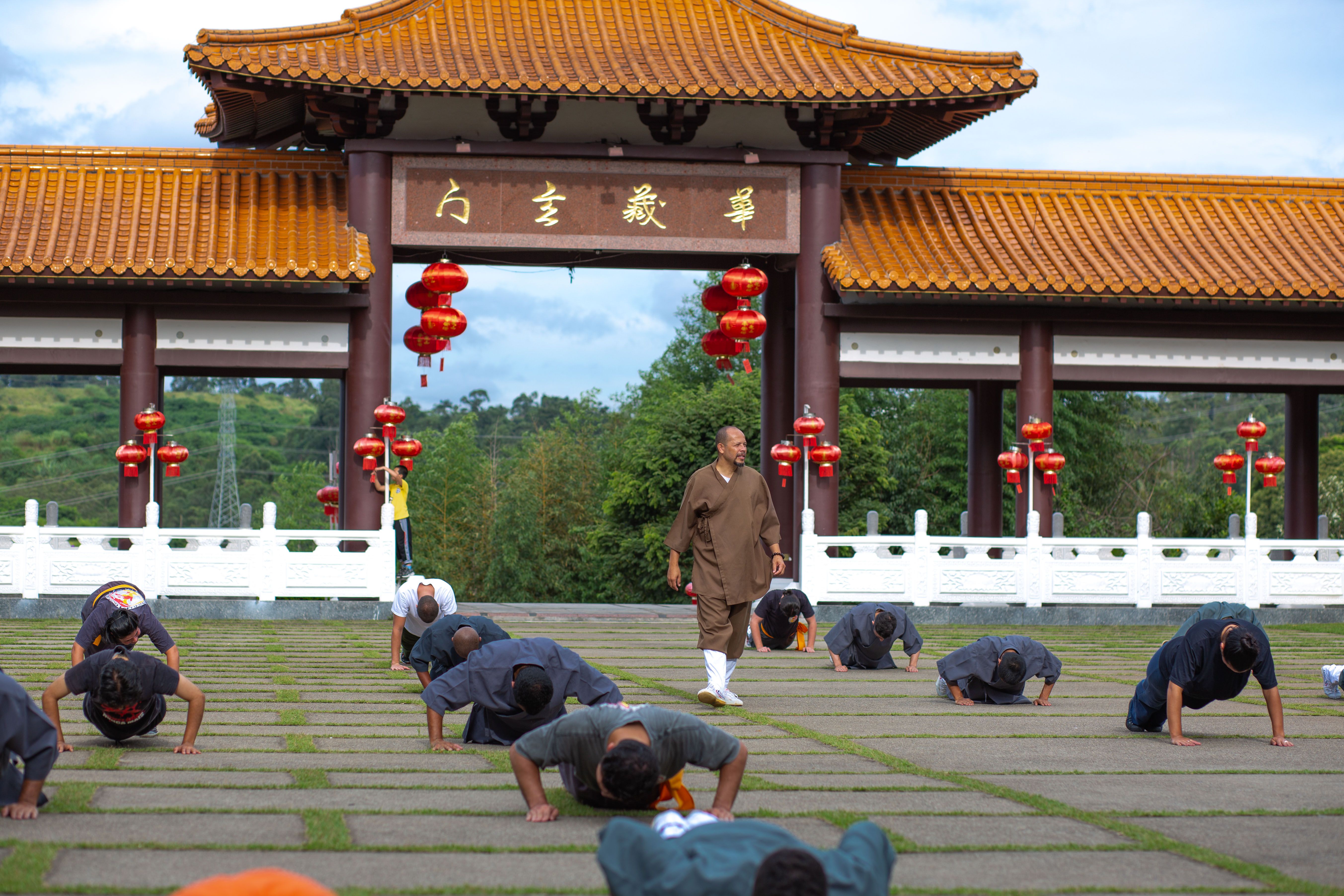 Martial artists practice at a temple courtyard under traditional architecture.