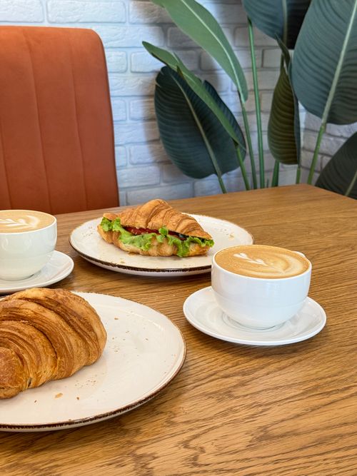 Free A cozy breakfast setup with croissants and cappuccinos on a wooden table. Stock Photo