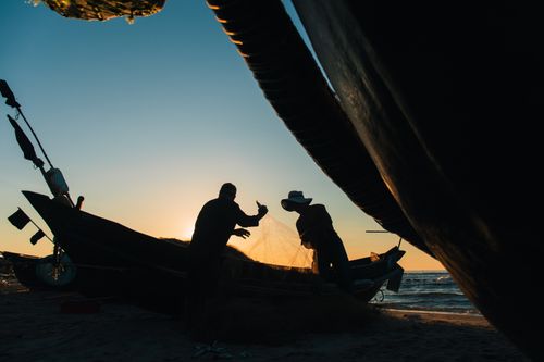 Free Silhouetted fishermen handle nets at sunrise in Quảng Trị, Vietnam, capturing a serene maritime moment. Stock Photo
