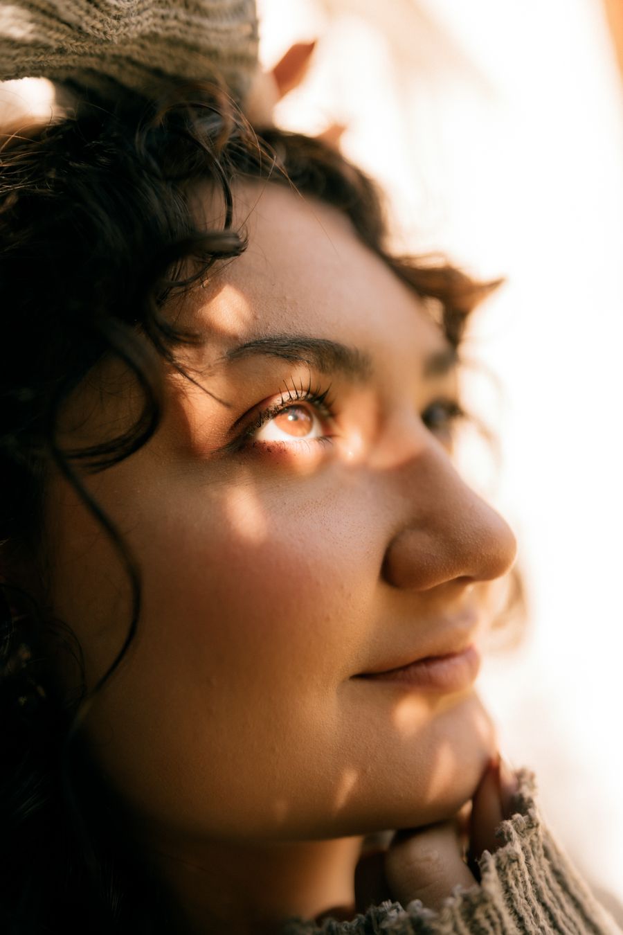 Close-up portrait with shadow patterns falling across the face in warm natural light. Photo by Alexander Mass on Pexels