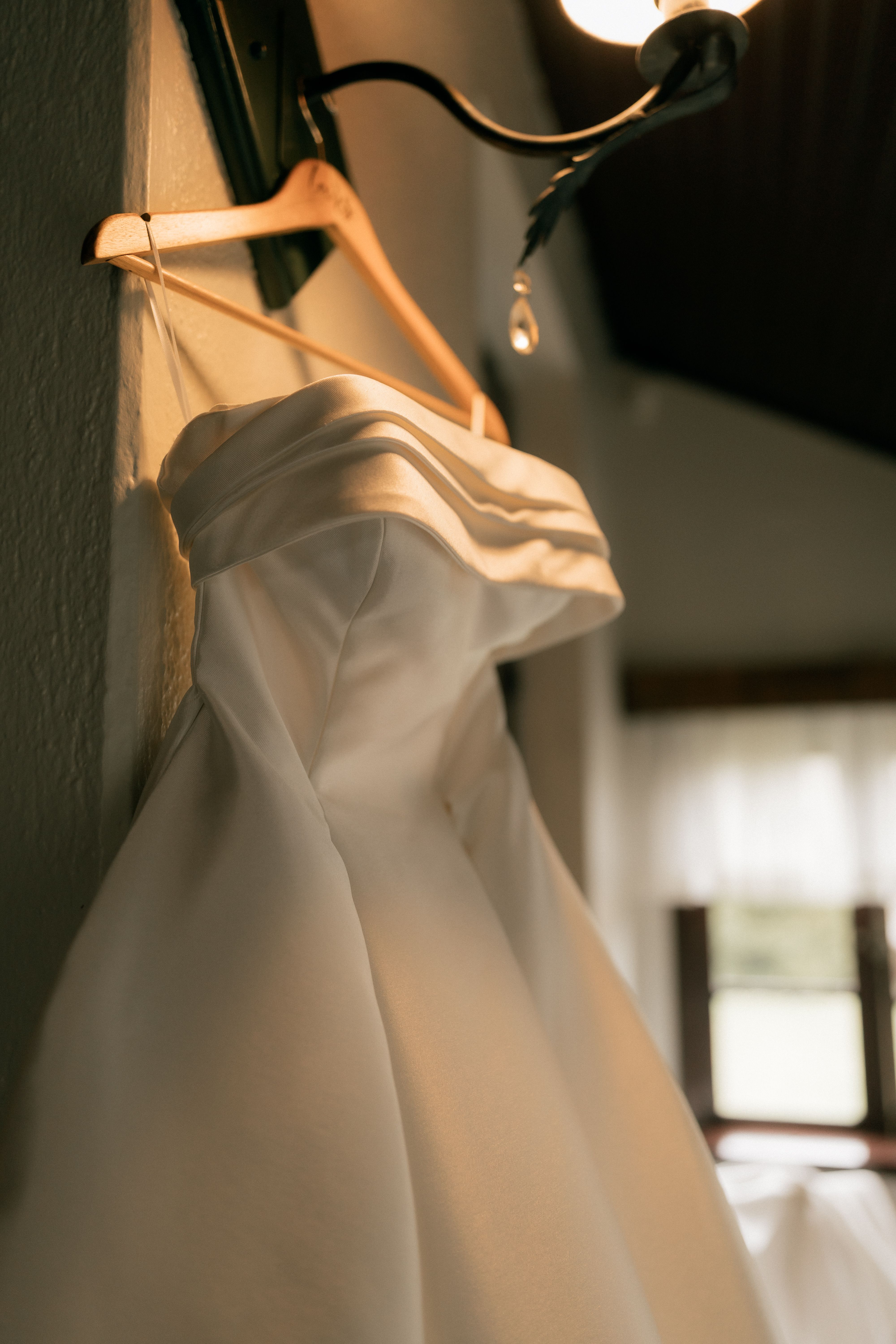 A wedding dress hanging in soft light
